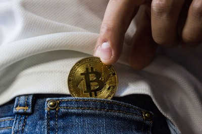 Muž si vkladá Bitcoin do vrecka nohavíc